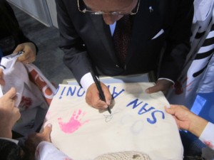 Dr. Abel Albino firmando la bandera con las manitos impresas de los niños de CONIN Areco